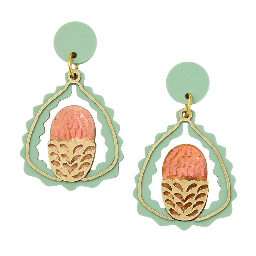 Pair of earrings with pink and gold banksia design on a light green background