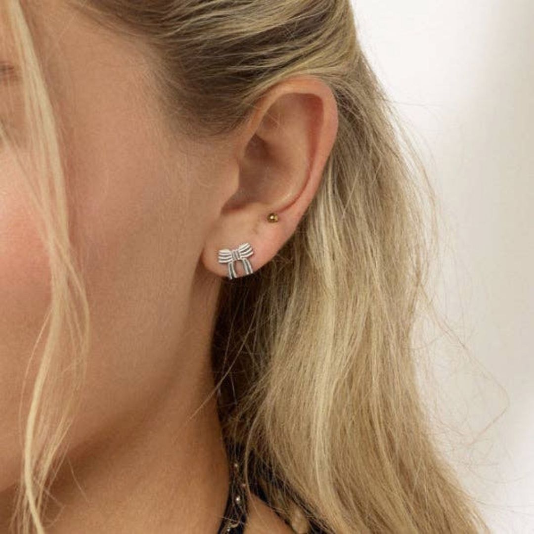 Bow-shaped silver earrings on a white background