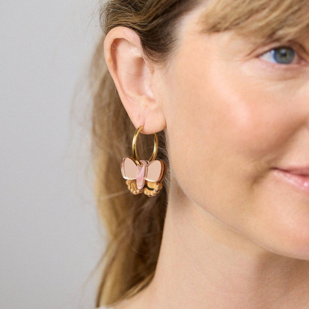 Butterfly-shaped earrings with gold and rose gold accents on a white background