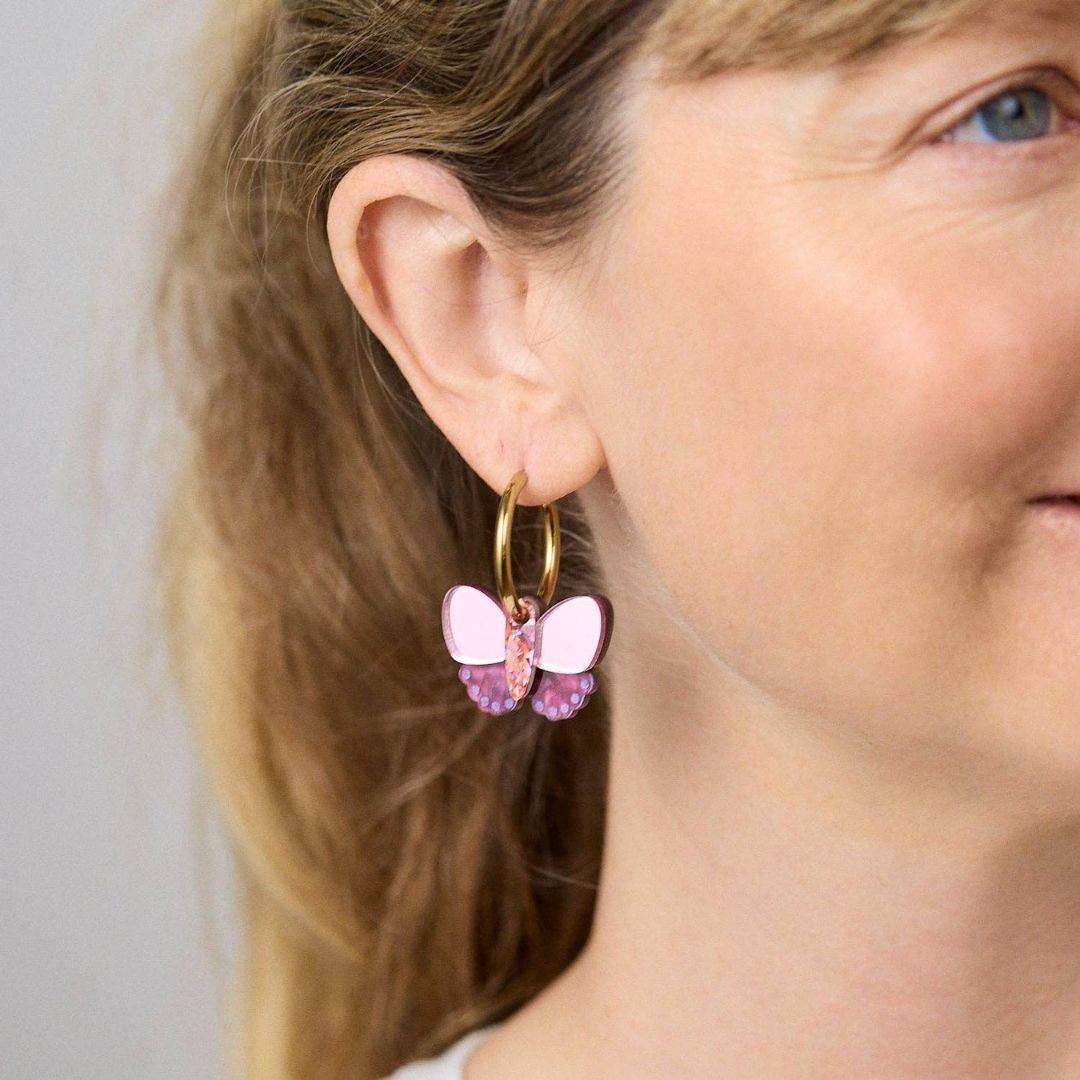 Butterfly-shaped earrings with plum and gold details on a white background