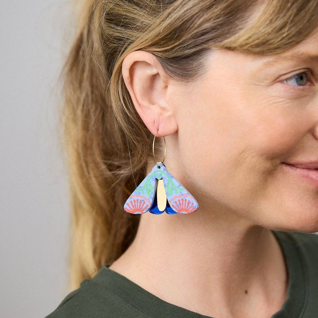 Periwinkle cobalt moth-shaped earrings on a white background