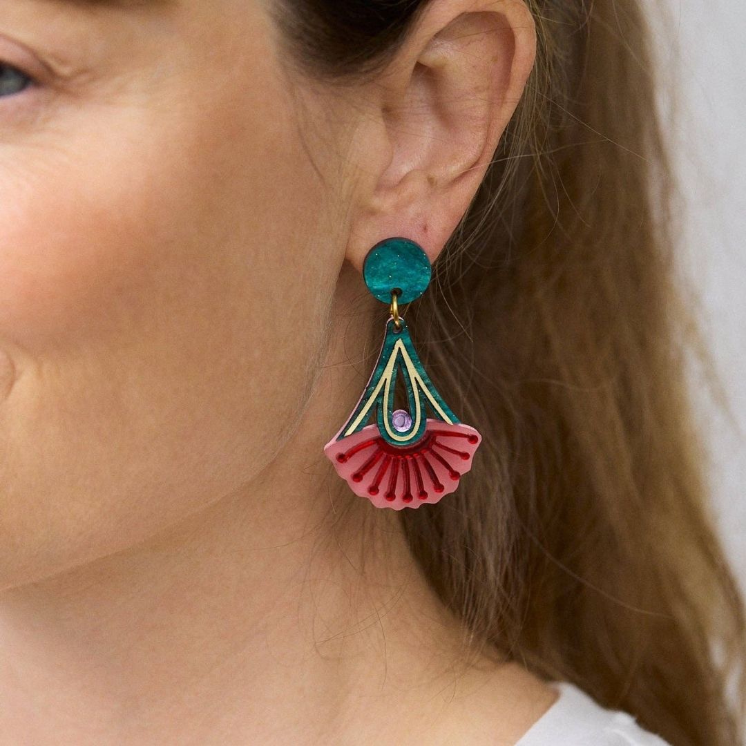 Pair of earrings with green, gold, and red design on a white background