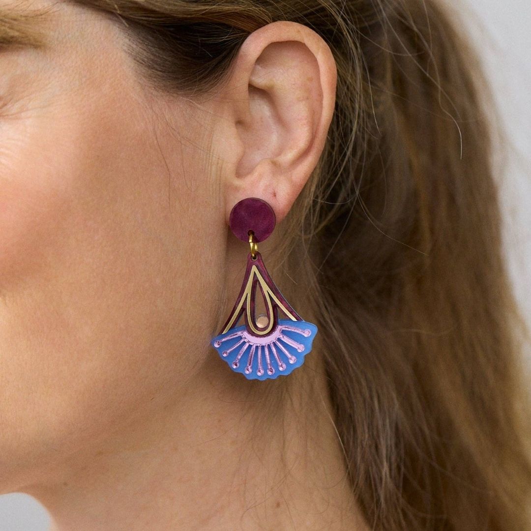 Pair of earrings with plum and blue  floral design on a white background
