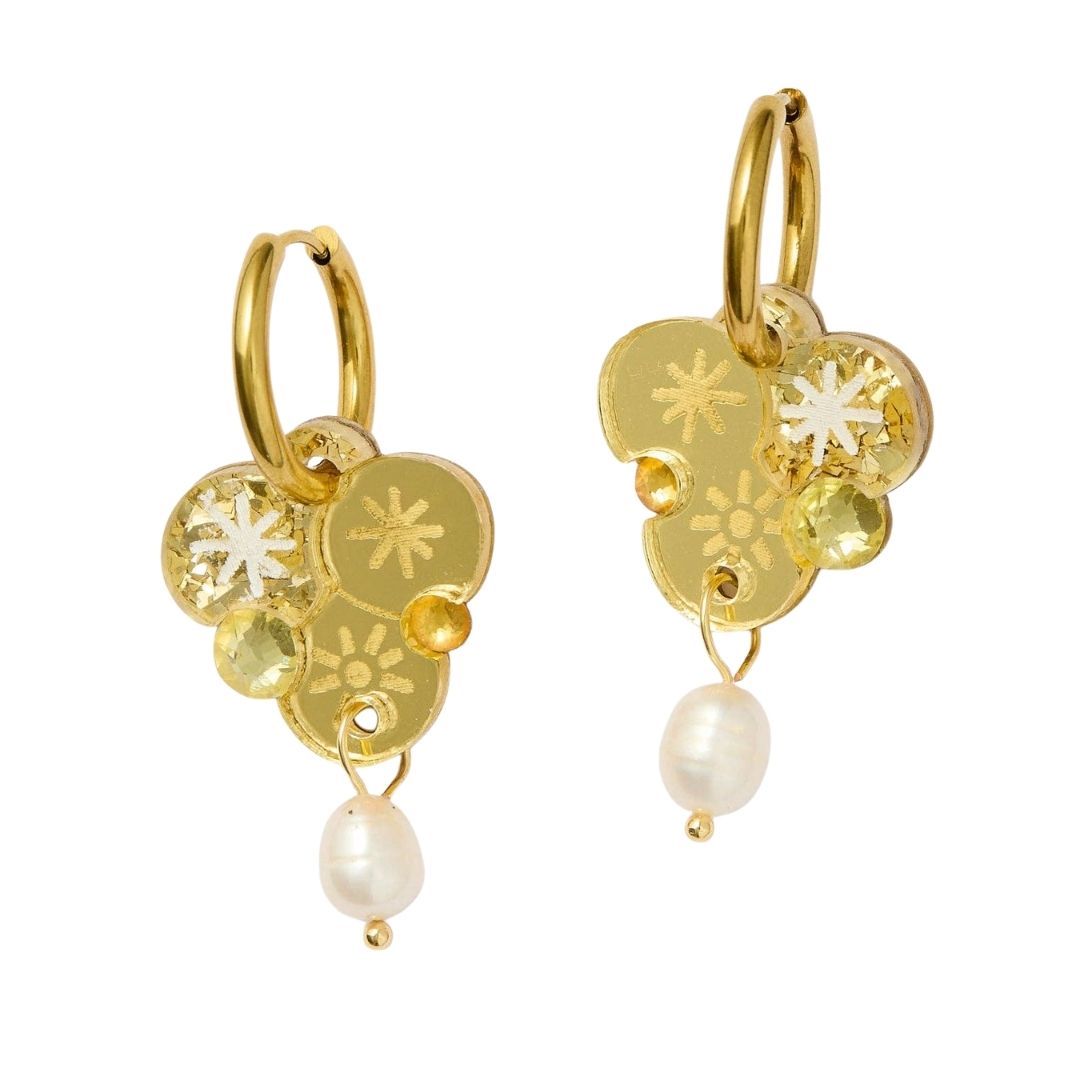 Gold earrings with wattle floral designs and pearls on a white background