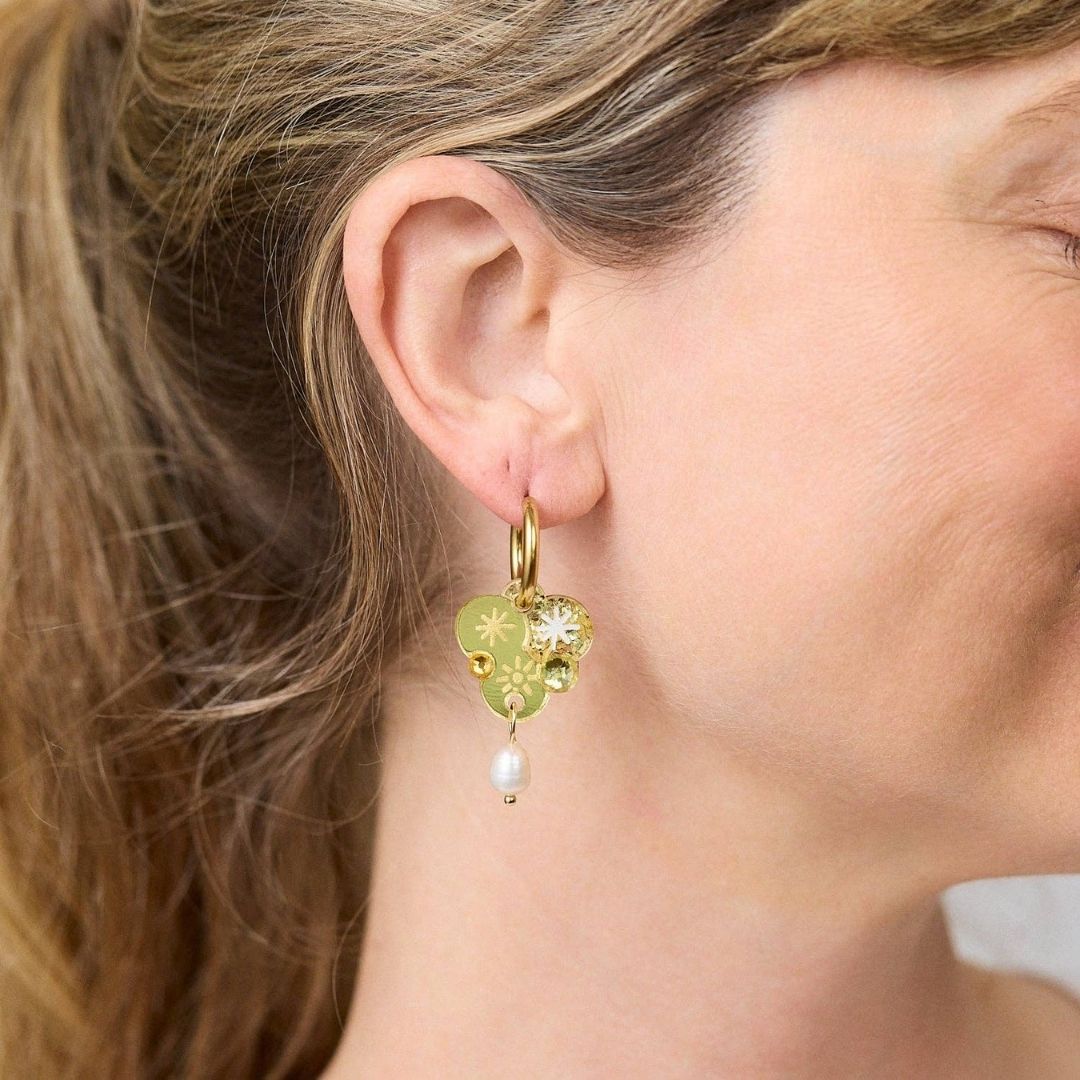 Gold earrings with wattle floral designs and pearls on a white background