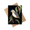 Greeting card with a bird design on a black background, placed on a brown envelope.