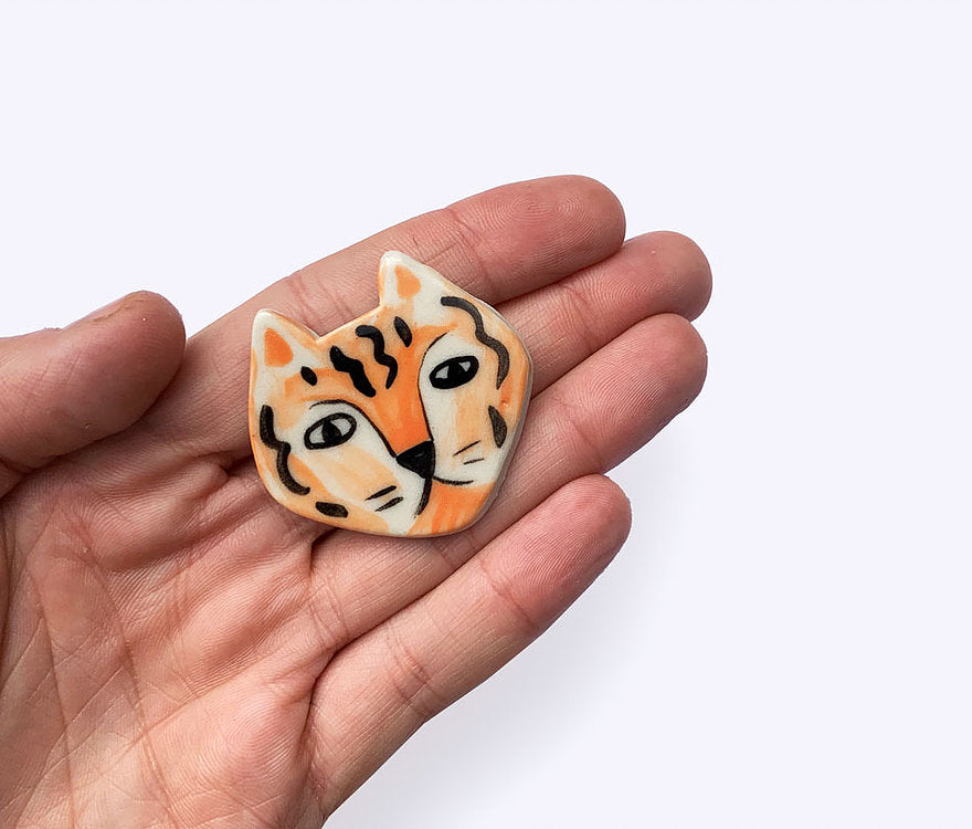 Togetherness design -The Tiger brooch features a hand built ceramic piece that will add a playful touch to your outfit. Features a silver metal clasp on the reverse.